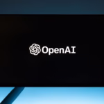 Minimalist display of OpenAI logo on a screen, set against a gradient blue background.