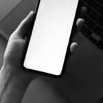 Monochrome photo of a smartphone held over a laptop for tech-themed design.