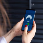 Close-up of a woman's hands using a VPN app on a smartphone, emphasizing digital security.