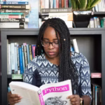 African American woman studying Python programming in a library setting.