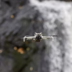 A drone captured mid-flight against a stunning waterfall backdrop in Sweden, showcasing technology in nature.