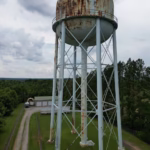 Aerial view of a rusted water tower surrounded by greenery in Campobello, South Carolina.