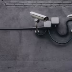 Two surveillance cameras mounted on a concrete wall, highlighting security technology.