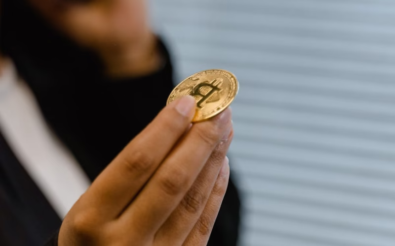 Portrait of a woman holding a Bitcoin, symbolizing digital finance and cryptocurrency trends.