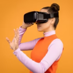 Woman with VR headset immersed in a virtual reality experience against an orange background.