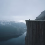 Dramatic view of Preikestolen cliff in Norway with mist and fjord.