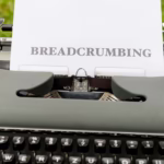 Close-up of a vintage typewriter outdoors with paper reading 'BREADCRUMBING'.